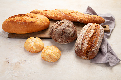 Assortment of various delicious freshly baked bread on white background, top view.