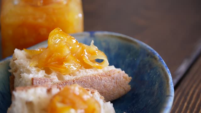 A video of spreading citrus marmalade on a baguette.