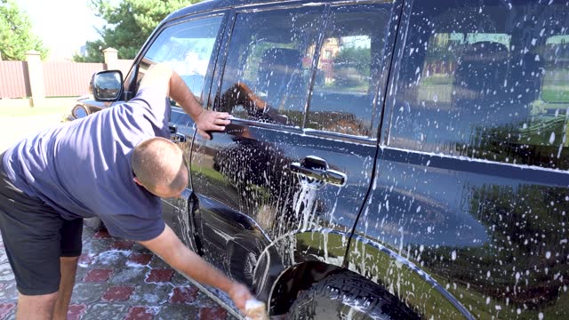 man washing car with car wash - pressure washer , vacuum cleaner, shampoo, sponges and microfiber car towels