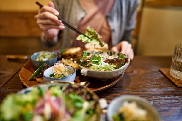 close-up of an asian woman enjoying a vegan meal at a vegan restaurant. - food vegan food gourmet vegetarian food imagens e fotografias de stock