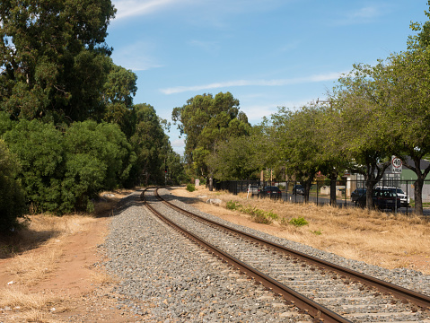 South Australia, Australia – February 12, 2020: View of a railway track winding around a corner with trees laden with green leaves.