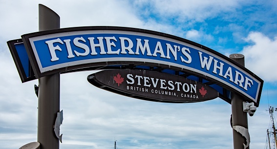 A vibrant blue sign with white lettering outside a fish restaurant announcing 'Fisherman's Wharf