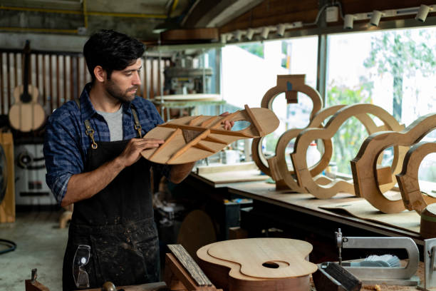 istock Luthier Taps Acoustic Guitar Wood to Check Sound Quality 1730956526