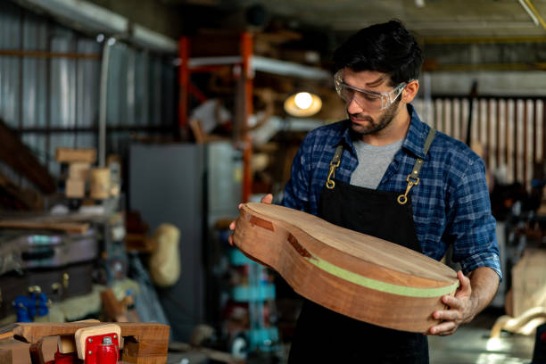 istock Luthier Holds Unfinished Acoustic Guitar Body in Workshop 1730957080