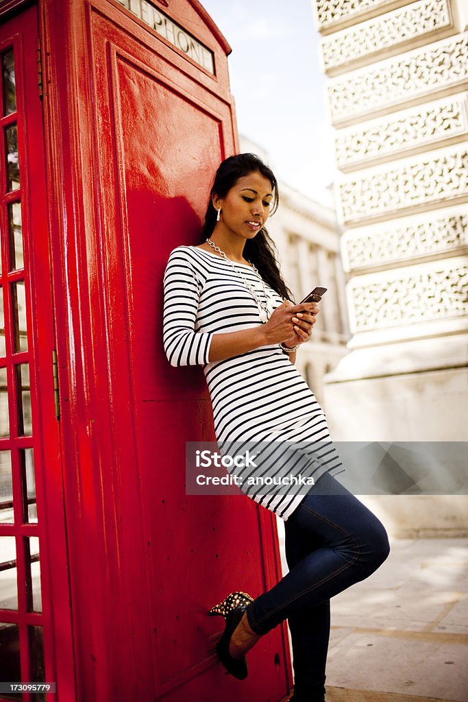 を使用して幸せな若い女性の携帯電話のブースの近く - インド人のロイヤリティフリーストックフォト
