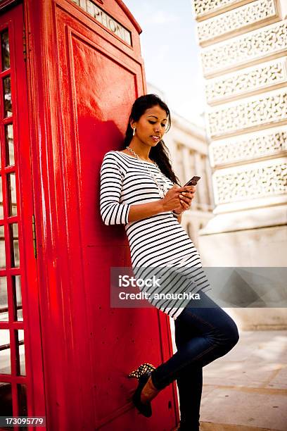 Mulher Jovem Feliz Usando Seu Telemóvel Perto De Cabine Telefónica - Fotografias de stock e mais imagens de Ao Ar Livre