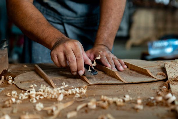 istock Guitar luthier using small planer to fine-tune bracing of acoustic guitar. 1730962110