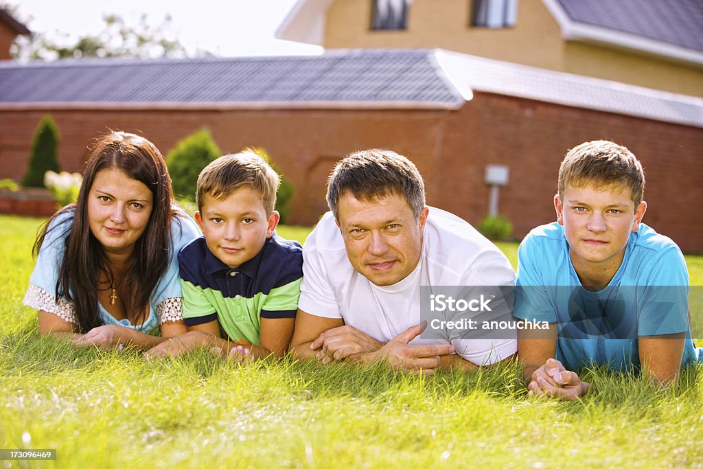 Famiglia con due bambini Sdraiato su un erba - Foto stock royalty-free di 10-11 anni