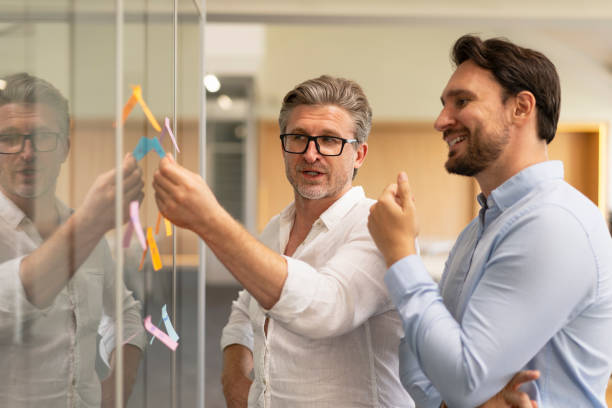 Colleagues talking using sticky notes working together in modern office. Teamwork Business people, colleagues talking using sticky notes working together in modern office. Teamwork scrum stock pictures, royalty-free photos & images