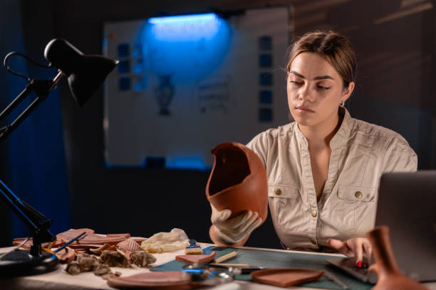 istock Female Archaeologist doing research working late night in office, using laptop computer, analysing ancient civilization culture artifacts 1730986018