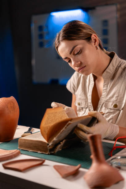 istock Archeologist working late night in office reading book and studying pottery vase 1730986020