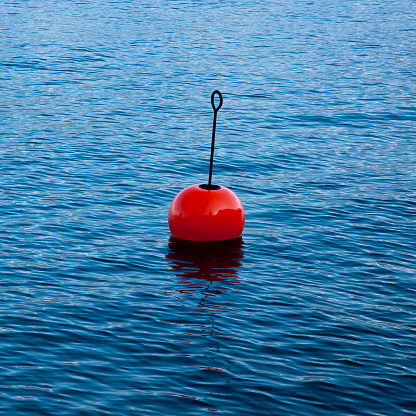 Plastic red bouy on a calm lake isolated on blue background