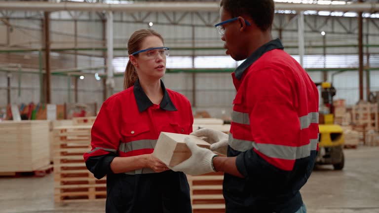 inspector explains a piece to a worker in a pallet wood factory.