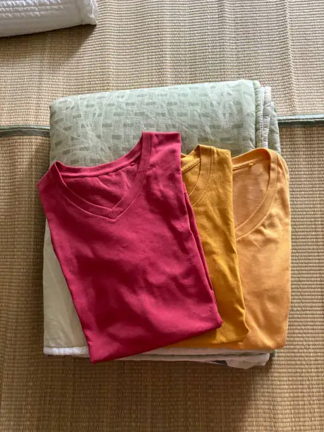 Folded clothes and quilt on bed. Mastercard Creative