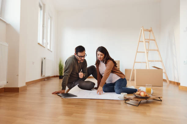istock Young pregnant couple analyzing blueprints after moving into a new home. 1731046929