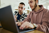 Male college students cooperating while e-learning in campus.