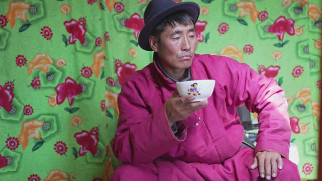 Mongolian man drinking tradition milk tea inside yurt