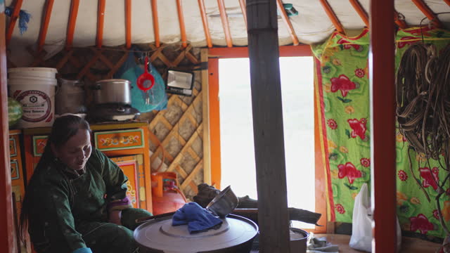 Mongolian nomad woman preparing milk tea for guest inside Ger