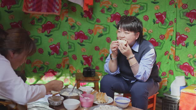 Asian Chinese female tourist trying homemade butter with bread in Mongolian yurt