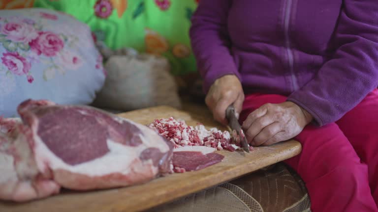 Mongolian woman cutting lamb meat preparing buuz