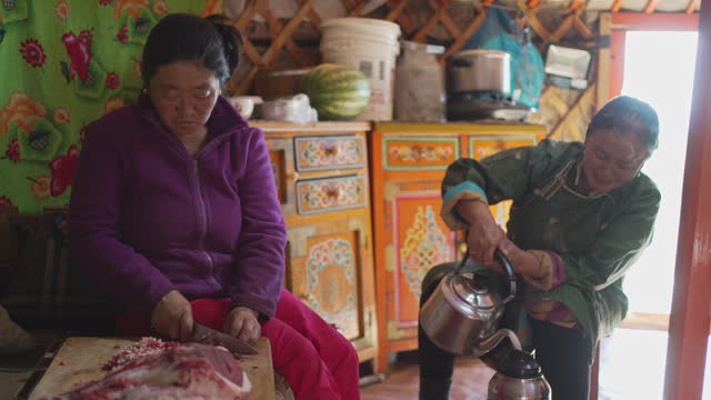 Mongolian Nomad women preparing food in yurt for guests