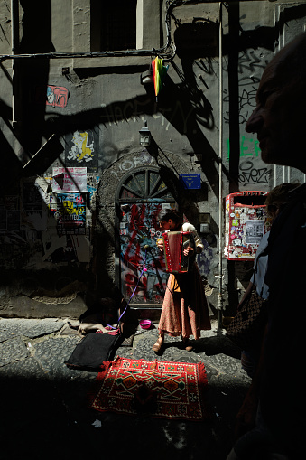 Naples, Italy - May  7, 2023: Accordion player on a street in Naples, some people walking around in the street