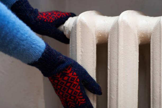 istock Human warming up hands in mittens near Hot Water Radiator. Space for text 1731106436