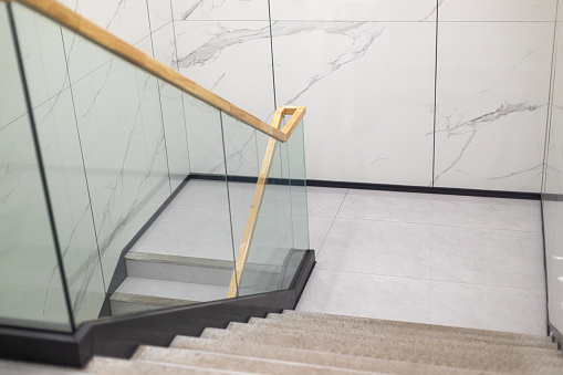 Downhill staircase with tiles and railings on the wall, construction stairs