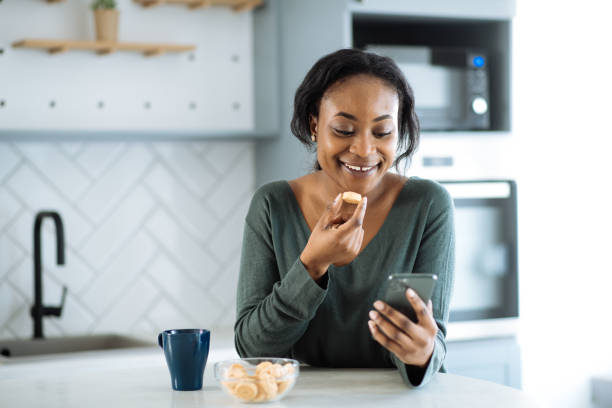 istock Casual African woman using smart phone app in kitchen 1731114660