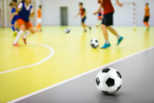 Indoor soccer training class for children. Soccer skills training. Futsal players in practice game at sports hall