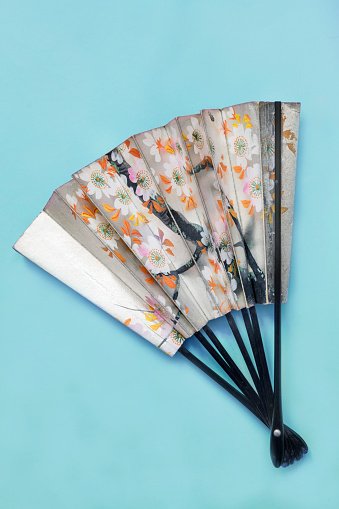 Vintage japanese paper hand fan on blue studio background