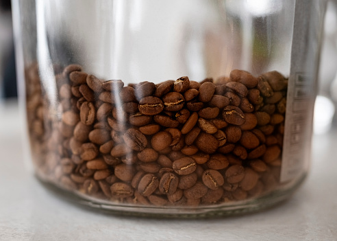 Fresh roasted coffee beans in a transparent glass jar placed on cafe counter