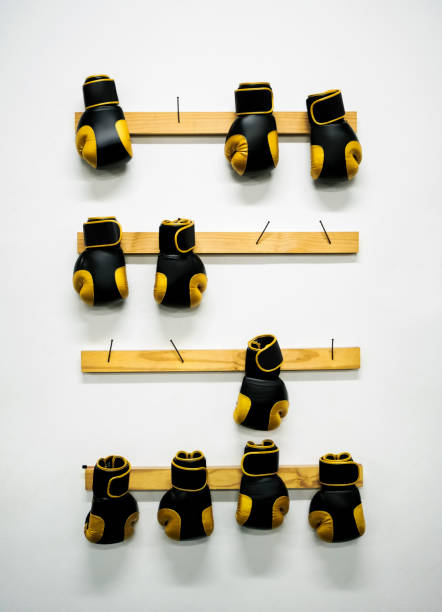 Black and yellow boxing gloves for training hanging on a gym wall