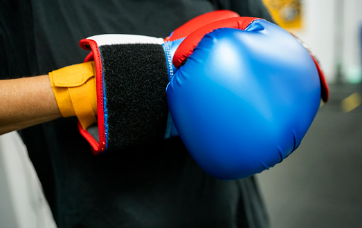 Close-up of woman putting on her boxing gloves for training at a gym