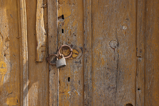 Locks and a padlock and chain on an old house door with peeling paint