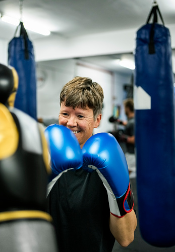 Smiling female boxer during training with her coach at a boxing studio