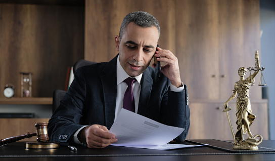 Legal consultant lawyer having a phone conversation with his client in his office.