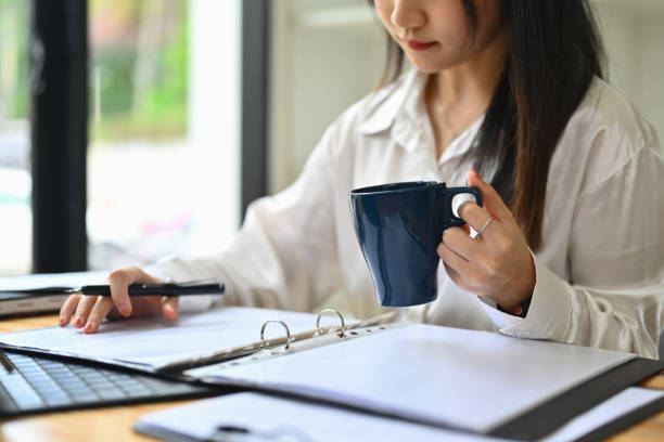 istock Female economist holding coffee cup working with sales statistics document at office desk 1731175683