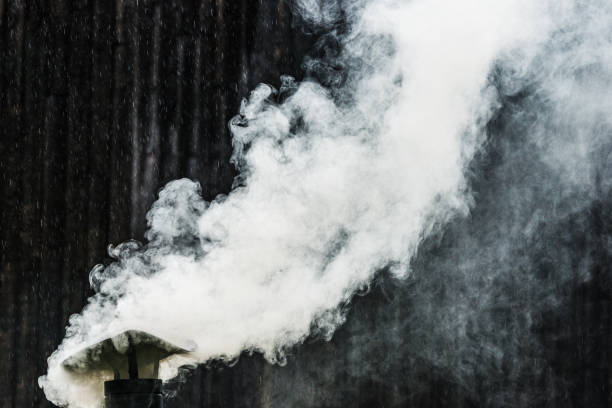 A chimney releases smoke in the rain.
