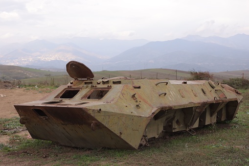 A vintage military tank with an antenna located on its turret top, situated in a remote desert setting