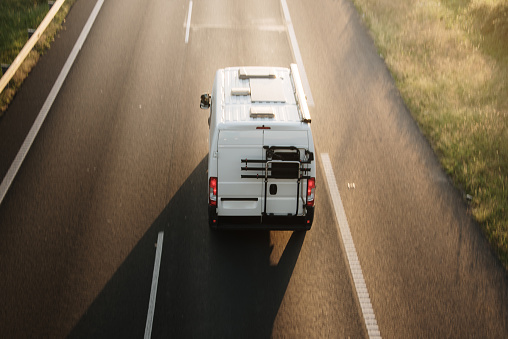 A camper van in motion on a two lane highway at sunset