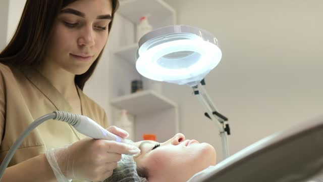 A close-up of a girl's face at a beautician doing ultrasonic cleaning of her face.