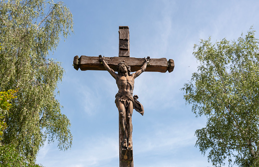 A wooden crucifix fastened to a stone pillar in a church.