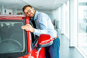 Man hugging and showing his love to a car at auto dealership
