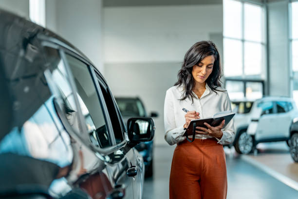 Serious saleswoman working at a car dealership Serious saleswoman working at a car dealership saloon car stock pictures, royalty-free photos & images