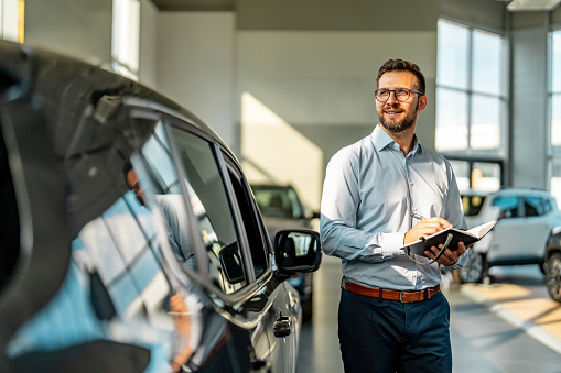 Car salesperson working at the dealership and taking notes