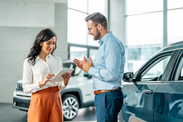 Cheerful car dealership customer talking to auto sales consultant stock photo