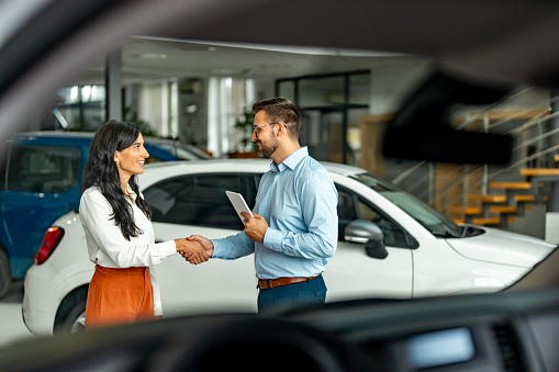 Buyer of the car shaking hands with the seller in auto dealership