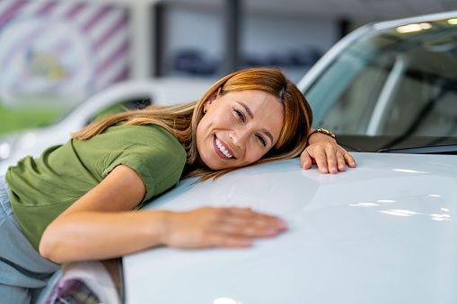 Pretty young woman hugs her new car