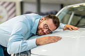 Man with eyes closed hugging a car in auto salon